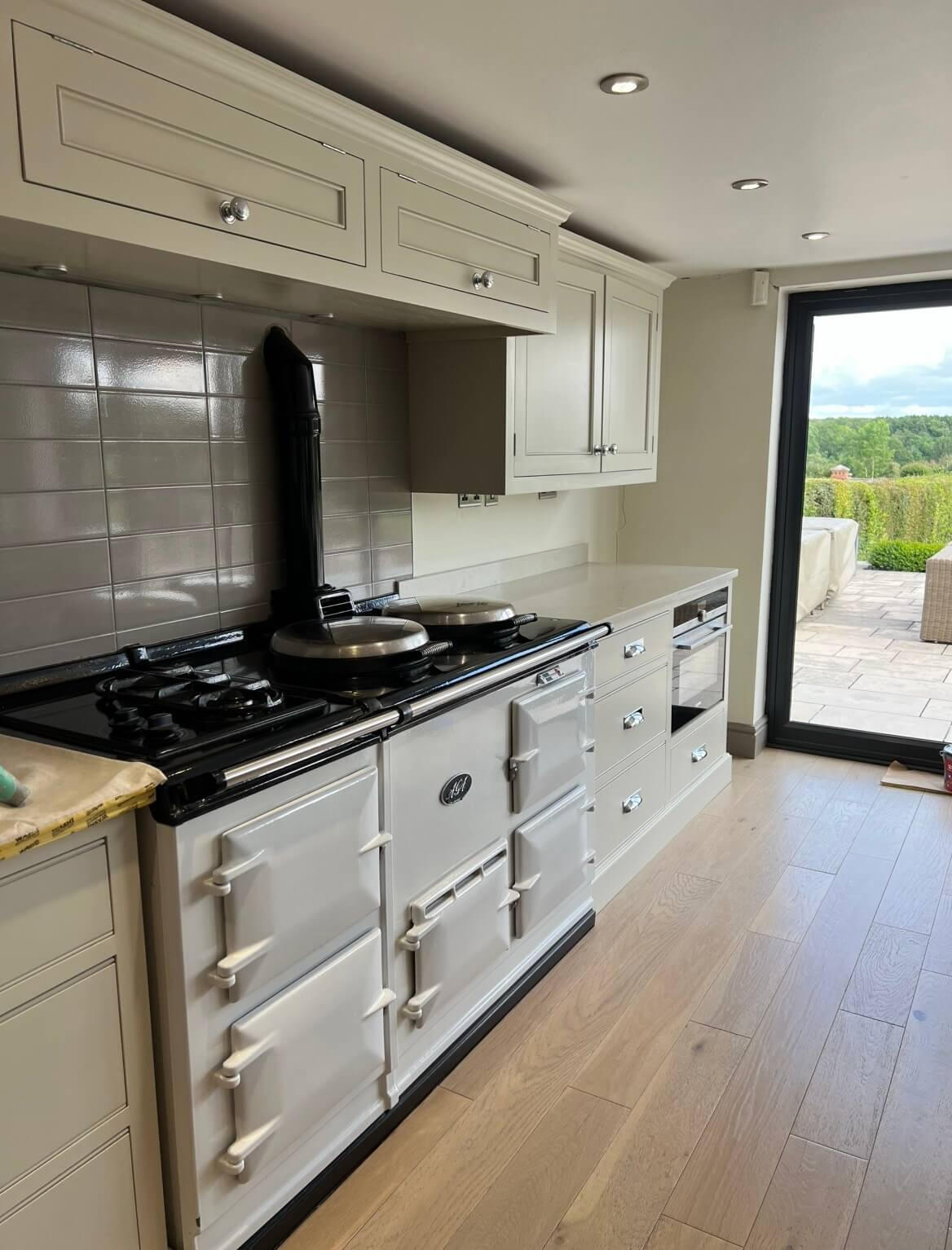 Hand-painted shaker kitchen cabinets in a warm neutral finish by Wilkinson Specialist Sprays.