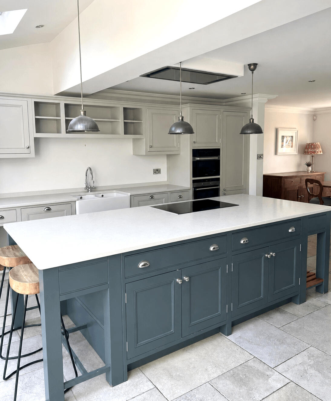 Two-tone shaker kitchen before cabinet repainting with light grey wall units and a blue kitchen island by Wilkinson Specialist Sprays.